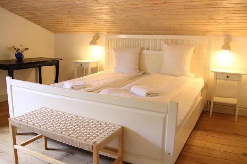 a large white bed with a bench in a room at The Lodge in Borre