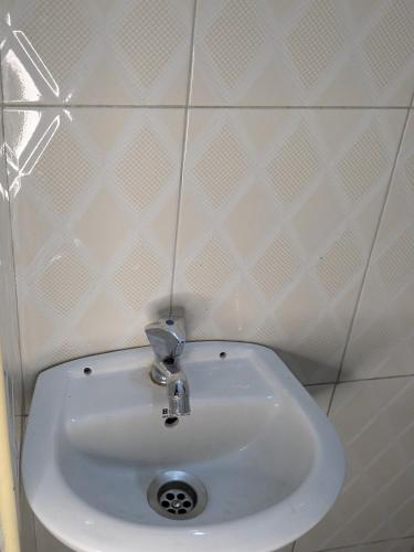 a white sink in a bathroom with white tiles at Masaka BnB in Masaka