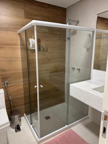 a glass shower in a bathroom with a sink at Guarajuba com 5 suítes, piscina e espaço gourmet in Camacari