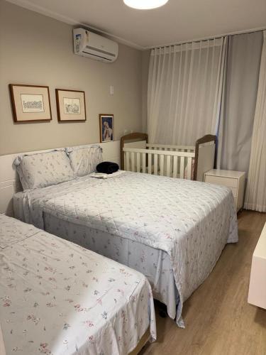 a bedroom with two beds and a cat sitting between them at Guarajuba com 5 suítes, piscina e espaço gourmet in Camacari
