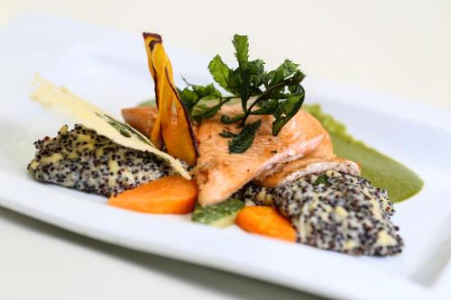 a white plate of food with fish and vegetables at Xima Exclusive Cusco in Cusco