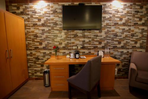a desk with a chair and a television on a wall at Xima Exclusive Cusco in Cusco