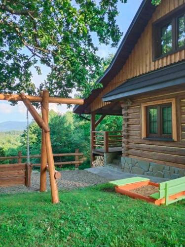 a log cabin with a swing in front of it at Chatka Pod Dębem in Rozdziele