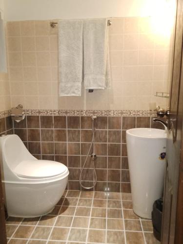 a bathroom with a toilet and a sink and towels at Royal Inn Hotel in Karachi