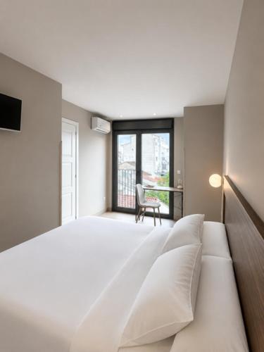 a bedroom with a large white bed and a chair at Escolapios Centro in Monforte de Lemos