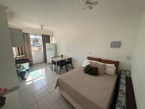 a bedroom with a bed and a table in it at Studio 1202 Confortável, Piscina e próximo a praia! in Guarujá