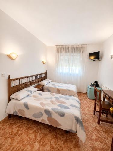 a bedroom with two beds and a desk and a table at Soutullo Praia in Sanxenxo