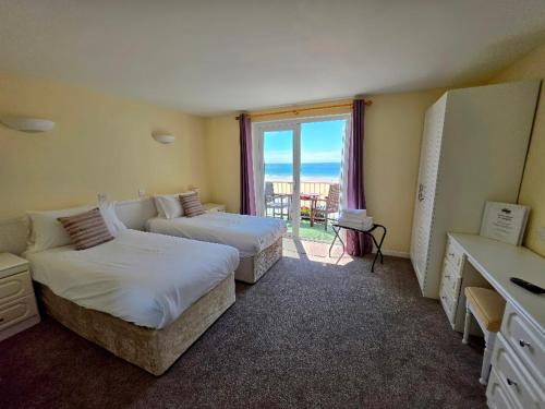 a hotel room with two beds and a balcony at Beau Rivage in St. Brelade