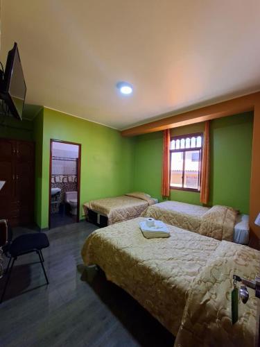 a hotel room with two beds and green walls at Hotel La Reserva INN in Ayacucho