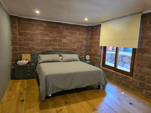 a bedroom with a bed and a brick wall at Casa Lago Colbun in Talca