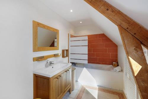 a bathroom with a sink and a mirror and a tub at Longère Colpernou in Plouguernével