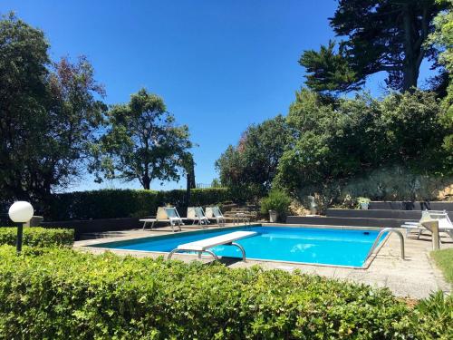 una piscina en un patio con sillas y árboles en Villa Domus 1938 en Sestri Levante