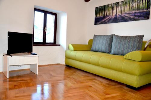 ein Wohnzimmer mit einem gelben Sofa und einem TV in der Unterkunft Holiday Home Archipelago in Lovran