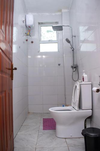 a white bathroom with a toilet and a shower at Vista del mar homes in Malindi