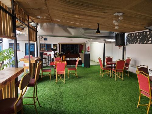 a room with chairs and tables and green carpet at Torchys in Kisumu