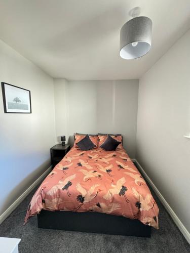 a bedroom with a bed with an orange comforter at Ogle Street 1-Bed Apartment in Armagh