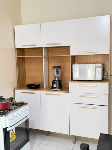a white kitchen with a stove and a microwave at Casa do Graf 2 in Sorriso
