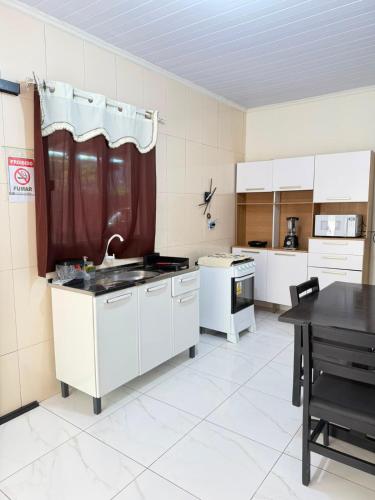 a large kitchen with white cabinets and a table at Casa do Graf 2 in Sorriso