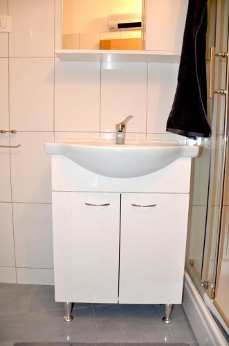 a bathroom with a white sink and a shower at Holiday Home Archipelago in Lovran