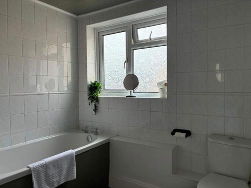 a bathroom with a tub and a toilet and a window at Delightful Durham Home in Gilesgate