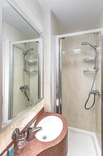 a bathroom with a sink and a shower with a mirror at The Nayland Hotel in London