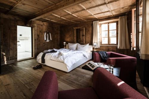 a bedroom with a bed and a couch and chairs at Hotel Weisses Kreuz in Burgusio