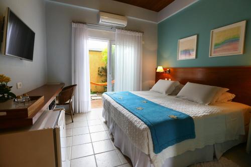 a bedroom with a bed and a desk and a window at Pousada Alcatrazes in Juquei