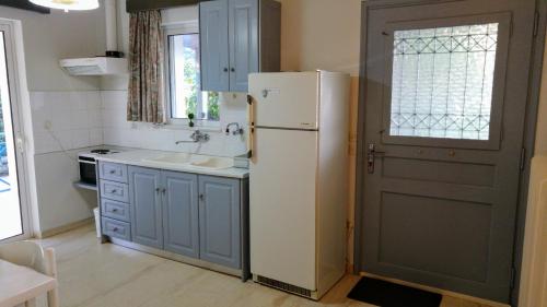 een keuken met een koelkast en een wastafel naast een deur bij V-Apartments in Tsoukalaíika