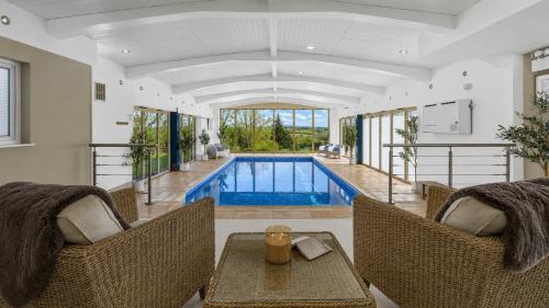 an indoor swimming pool with two chairs and a table at Ferny Retreat in Bromyard