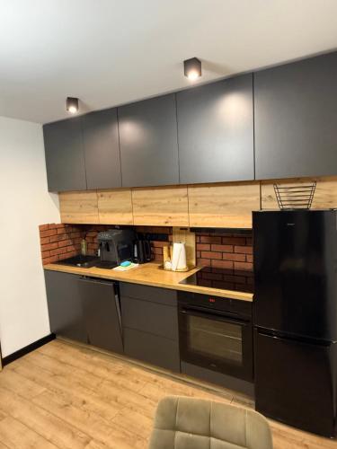 a kitchen with black cabinets and a black refrigerator at Apartament z Balią in Świeradów-Zdrój