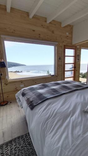 a bedroom with a large bed and a large window at Refugio en Tril tril in Bahía Mansa