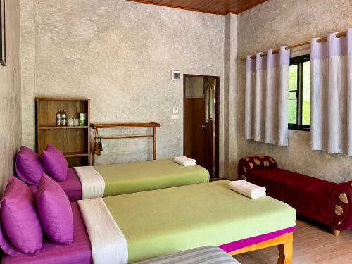 two beds with colorful pillows in a room at Maewin Resort in Ban Huai Rin