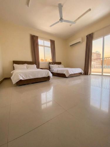 two beds in a large room with windows at Aknan Center Market in Salalah