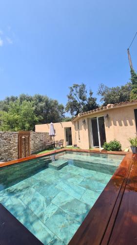a large swimming pool with a table and a house at Perla Di Macchia in Bonifacio