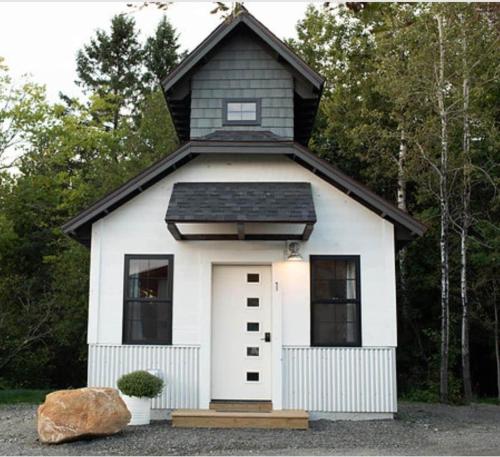 a small white house with a black roof at The Summit Suite | Walk to Rangeley Lake • ATV & Sled Access in Rangeley