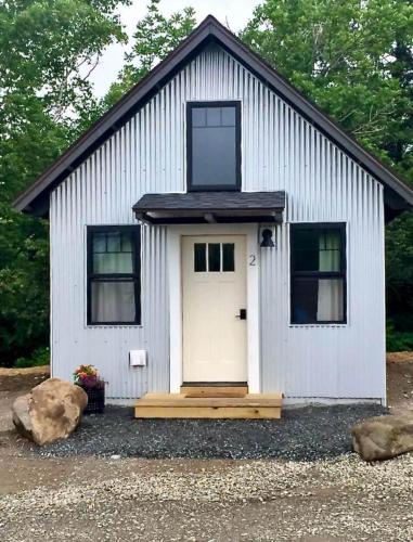 a small white building with a door and windows at The Lupine | Cross Stone Cabins • Walk to Rangeley Lake in Rangeley