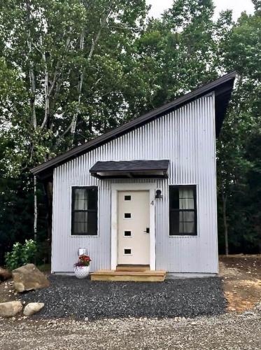 a small white shed with a door and windows at The Ridgeline | Near Saddleback • Walk to Rangeley Lake in Rangeley