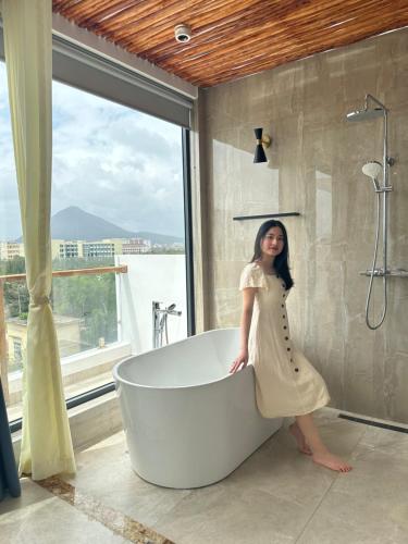 a woman standing next to a bath tub in a bathroom at Aviera Boutique in Liên Trì (4)