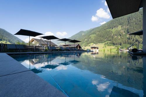 a pool of water with umbrellas on top at ELVA PREMIUM APARTMENT HOTEL inklusive Sommerpass STUBAI SUPER CARD in Neustift im Stubaital
