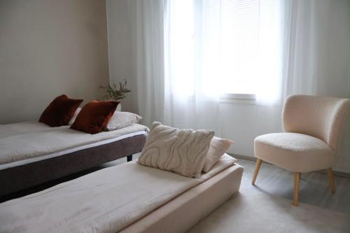 a room with two beds and a chair and a window at Villa Lydia Lapland - Private Sauna & Aurora View in Rovaniemi