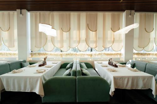 a dining room with two tables and green couches at Inzhu Premium Hotel in Taraz