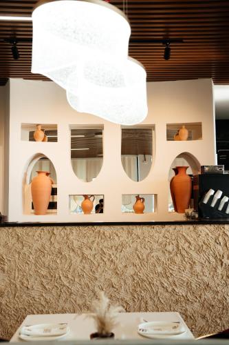 a chandelier above a table with vases on a wall at Inzhu Premium Hotel in Taraz