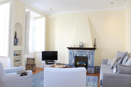 a living room with white furniture and a fireplace at Charming Duplex- Príncipe Real in Lisbon