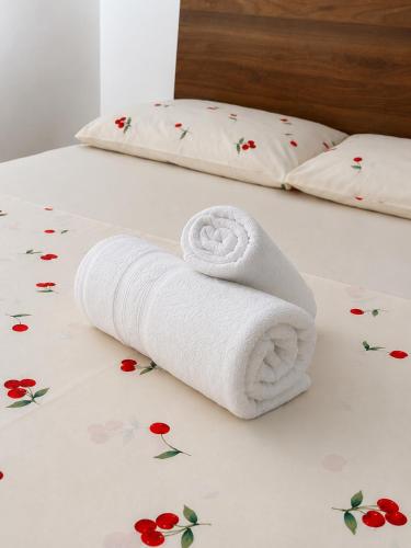 a white towel on a bed with flowers on it at Pousada São José in Joinville