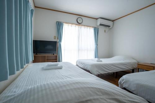 a hotel room with two beds and a window at Hotel Sunset ZANPA in Yomitan