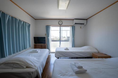 a room with two beds and a window with a clock at Hotel Sunset ZANPA in Yomitan