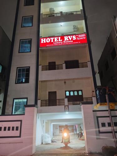 a person riding a motorcycle in front of a hotel ivrs building at Hotel 9 square in Shamshabad