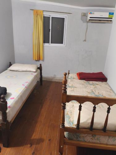 two beds sitting in a room with a window at El Rancho del Tucu in Colón