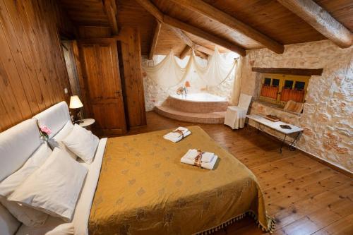 a bedroom with a large bed and a bath tub at Revera Traditional Stone Villas, Apartments & Studios in Keri