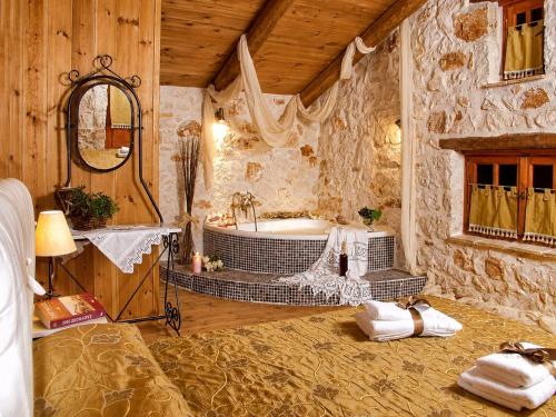a bathroom with a tub in a stone wall at Revera Traditional Stone Villas, Apartments & Studios in Keri